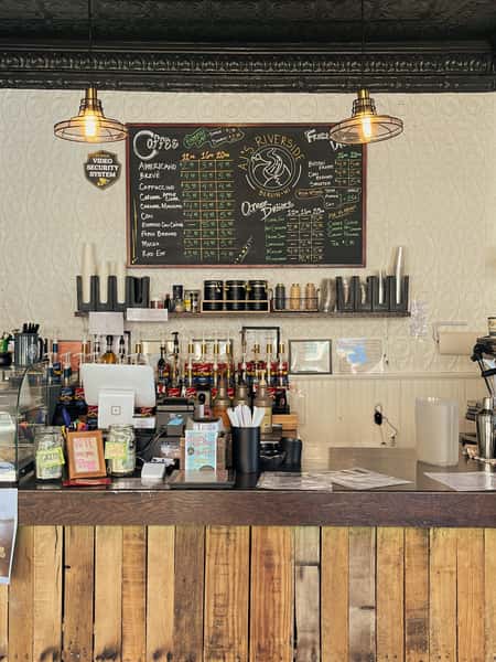 AJ's Riverside coffee shop counter with large chalkboard menu and rustic wooden front.