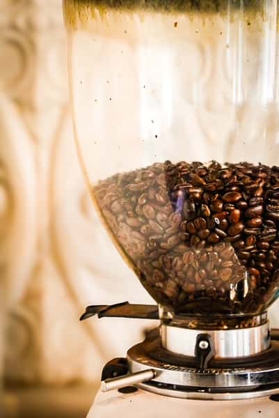 Coffee grinder hopper filled with brown coffee beans at AJ's Riverside.