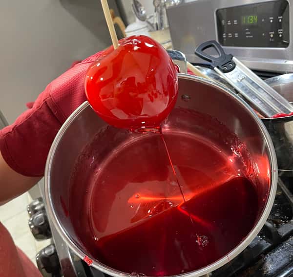 Candy apple dripping into a pot of syrup