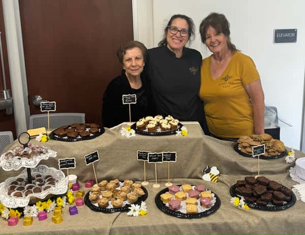 Happy owner with customers at a sweet-filled table