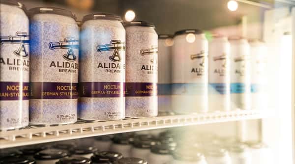 Alidade Brewing German-style black lager cans in a refrigerated display case.