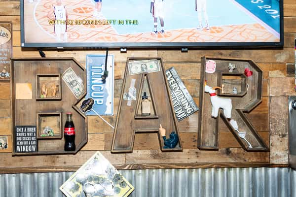 A worn wood sign with BAR spelled out and corrugated metal
