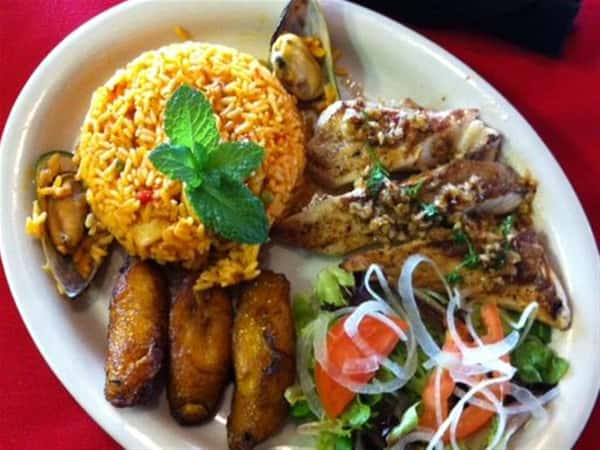 Top view of Chilean Sea Bass. Yellow rice, salad and fried plantains on the side.