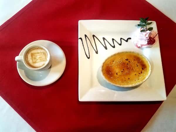 Top view of natilla catana (custard) with cocolate sauce and whipped cream. espresso on the side.