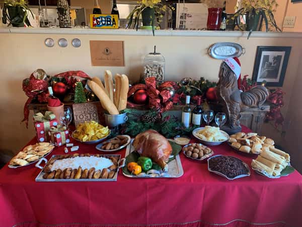 Catering display with assorted dishes of Cuban cuisine and bottles of wine with wine glasses