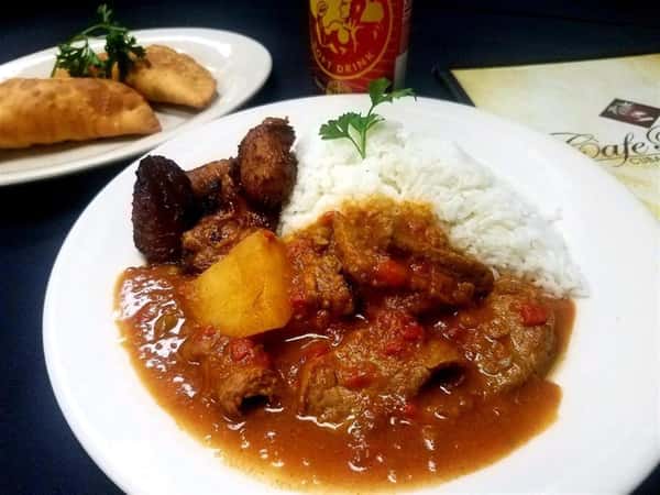 Pernil. Oven-roasted pork topped with our specialty garlic sauce. White rice and fried plantains on the side,