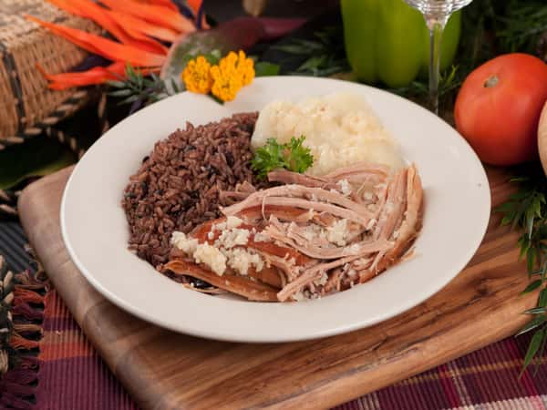 Pernil. Oven-roasted pork topped with our specialty garlic sauce. Mashed potatoes, rice and beans on the side.
