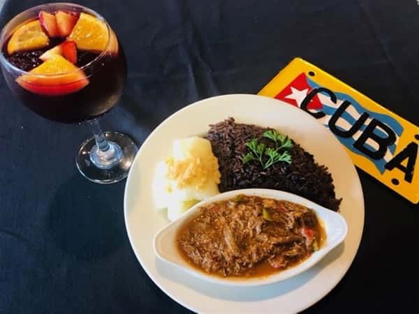 Ropa Vieja Shredded beef slow-cooked in tomato and wine sauce. cuban sign on the table beside the plate.