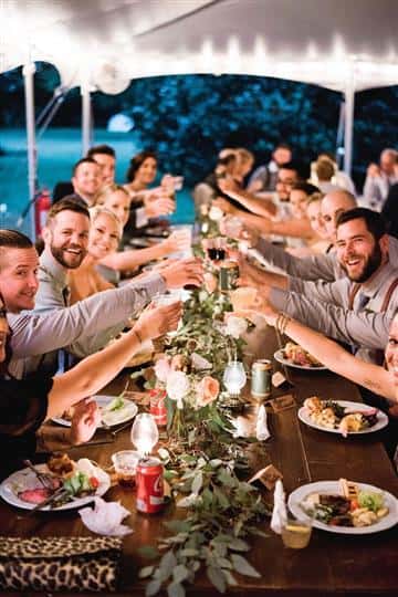 large table of people smiling at the camera making a toast