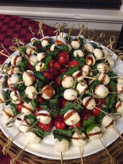 platter filled with mozzarella balls on skewers with tomatoes and spinach