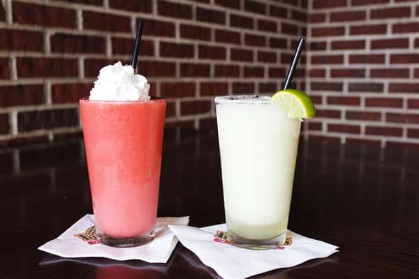 One pink smoothie with whipped cream on the top and a margarita with a lime wedge