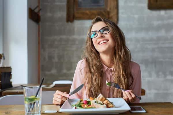 female wearing glasses smiling enjoying a meal