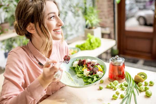 female smiling holding a plate full of salad