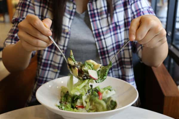 person mixing up a salad in a bowl