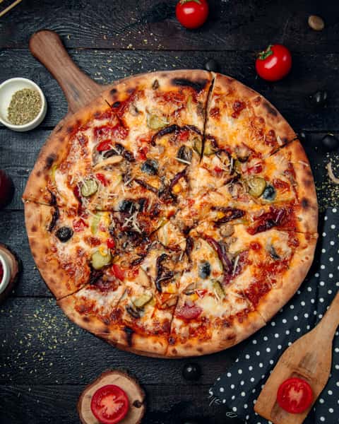 Cheezy Pizza's vegetable pizza sits on a wooden board.