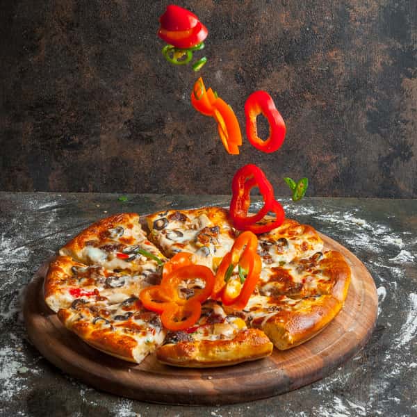 Cheezy Pizza's delicious-looking pizza with mushrooms and roasted red peppers is being topped with more peppers.
