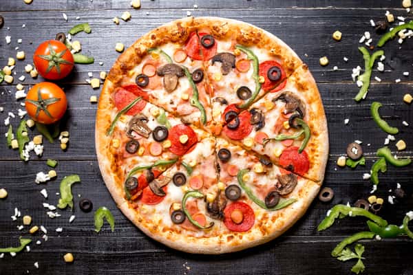 Cheezy Pizza's vegetable pizza with olives, mushrooms, and peppers sits on a dark wood surface.