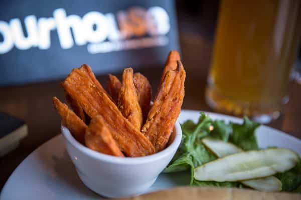 Crispy sweet potato fries in a white bowl with a side salad and craft beer, served at Pourhouse Bar & Grill in Loveland.