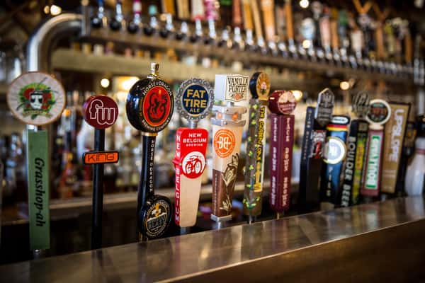 Rustic bar interior with wooden countertops, bar stools, draft beer taps, and liquor shelves at Pourhouse Bar & Grill in Loveland.