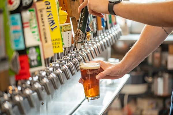 Freshly poured draft beer from a wall of taps into a pint glass at Pourhouse Bar & Grill in Loveland, showcasing the extensive craft beer selection.