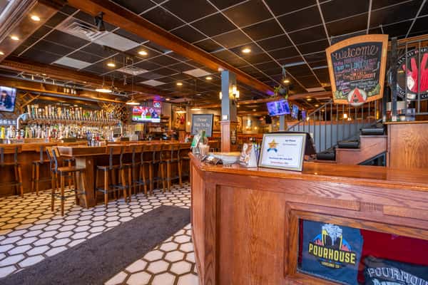 Rustic bar interior with wooden countertops, bar stools, draft beer taps, and liquor shelves at Pourhouse Bar & Grill in Loveland.