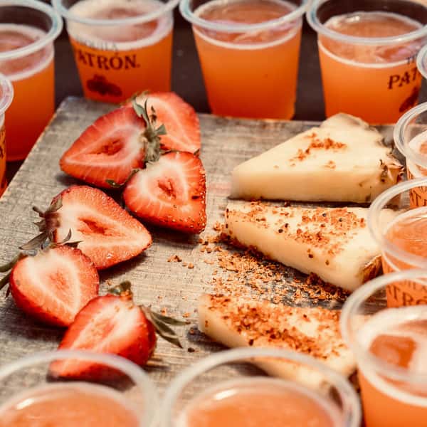 Tequila tasting flight with fresh strawberries and chili-rimmed cheesecake bites at a lively Mexican bar