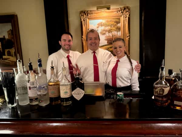 Restaurant bartenders and staff smiling behind the bar.