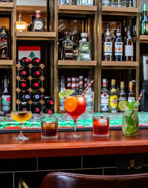 Craft cocktails and refreshing mojitos lined up at an elegant restaurant bar with premium spirits and wine display