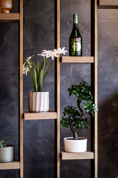 Modern restaurant shelf decor with potted plants, flowers, and wine bottle accents in a contemporary dining space