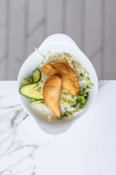 Crispy Mediterranean pastries served on fresh salad with cucumber and herbs in a modern restaurant setting