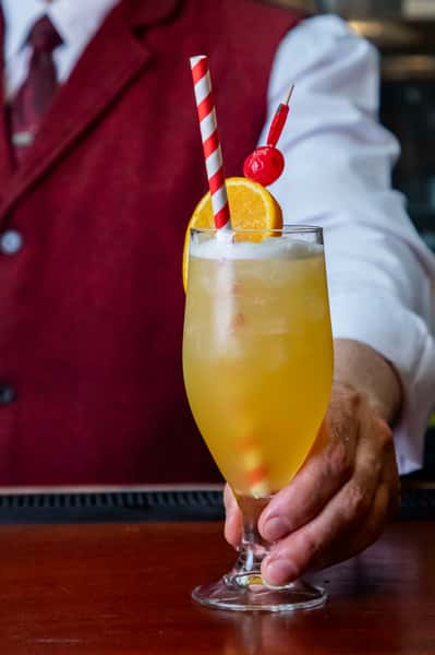 Refreshing citrus cocktail garnished with orange slice and cherry served at an upscale restaurant bar