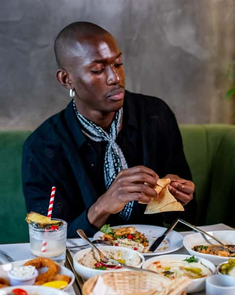 Guest enjoying pita bread and Mediterranean mezze with cocktails at a stylish modern restaurant