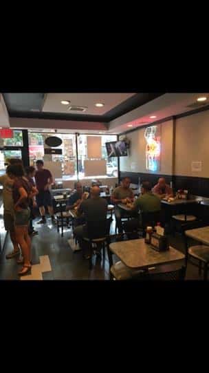 Customers sitting at three different tables and other customers on line to check out
