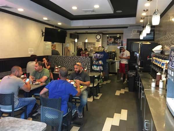 Customers sitting at three different tables inside the store eating and having a good time