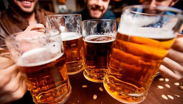 Group of friends clinking large beer mugs together in a lively toast.