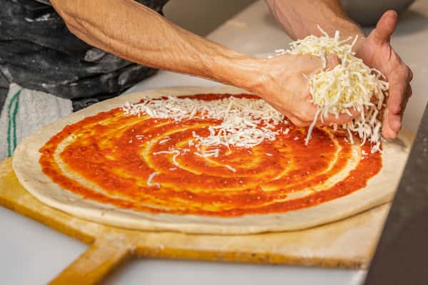 Pizza Chef adding cheese to pizza