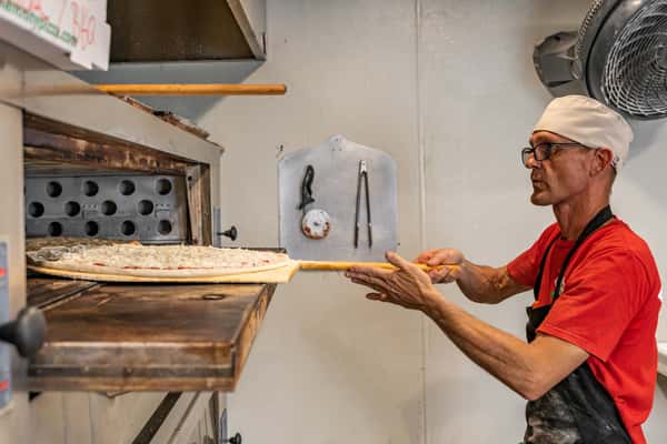 Pizza chef putting pizza in oven