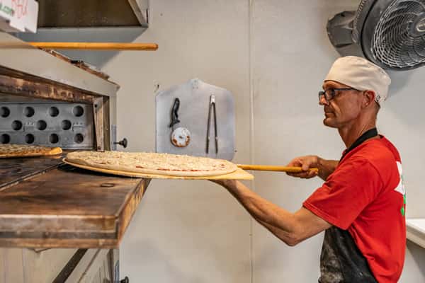 Pizza Chef putting pizza in oven
