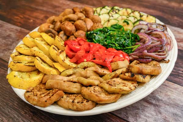 Platter of grilled vegetables including eggplant, zucchini, squash, mushrooms, spinach, onions, and roasted red peppers.