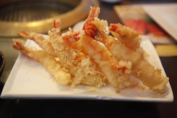 Golden crispy shrimp tempura served on a white rectangular plate.