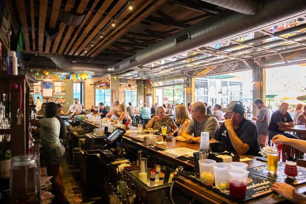 Busy interior of Crooked Hammock Brewery with patrons at the bar and tables, enjoying drinks in a lively, rustic atmosphere.