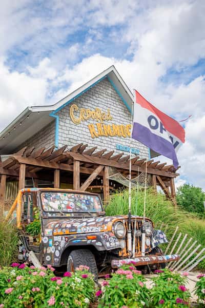 Crooked Hammock Brewery building with a red, white, and blue OPEN flag and a sticker-covered vintage Jeep out front.
