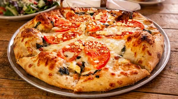 Tomato and feta pizza with melted mozzarella and green herbs.