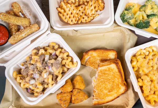 Assorted takeout containers with mac and cheese, waffle fries, and a grilled sandwich