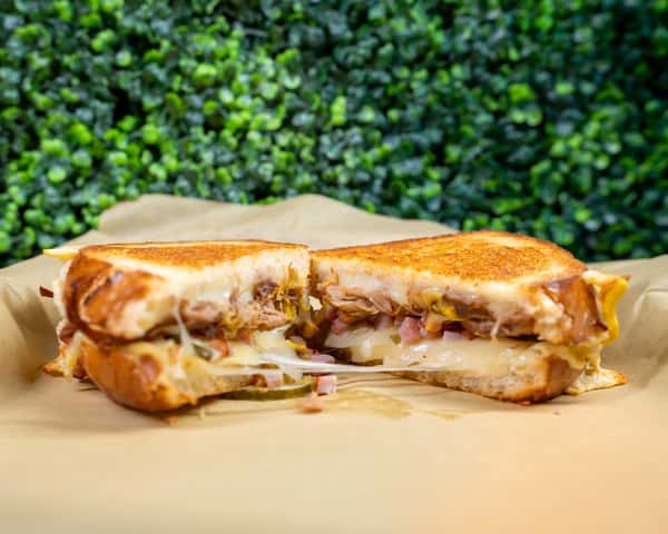 Grilled Cubano sandwich sliced in half showing melted cheese and ham