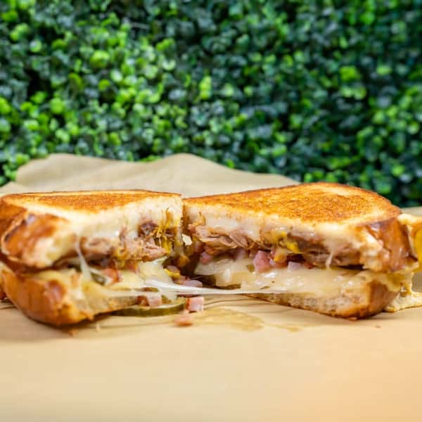 Grilled sandwich with melted cheese and meat served on parchment paper