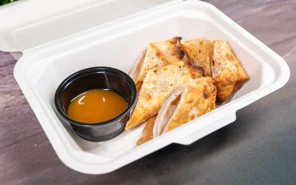 Toasted sandwich cut into triangles served in a takeout container with a side of dipping sauce