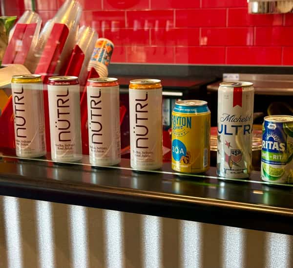 Canned beverages displayed on a shelf at the counter