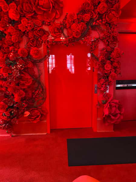 Picture of the door with an arrange of red flowers on top of the door with a red hue