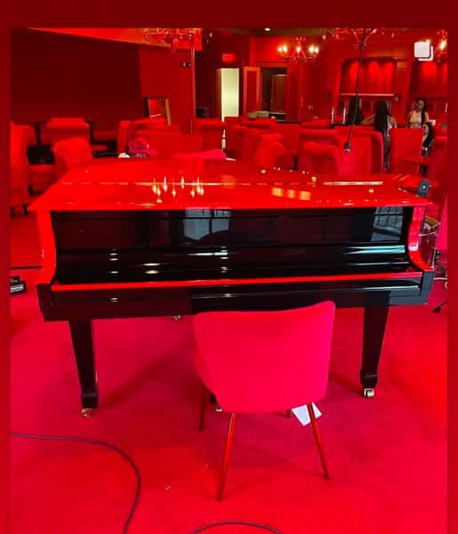 Black piano in the room with a red hue